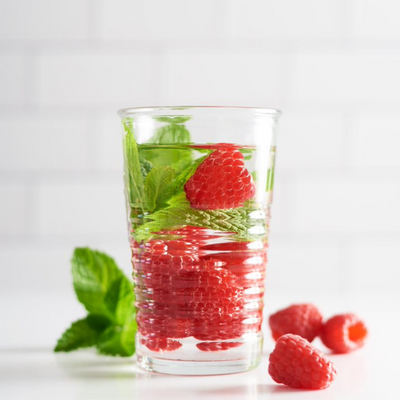 raspberries and mint leaves in a glass of water 